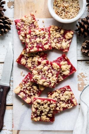 Cranberry Curd and Hazelnut Shortbread Bars on a white marble board lined with parchment paper.