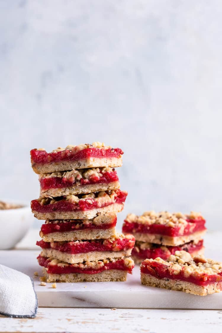 A stack of Cranberry Curd and Hazelnut Shortbread Bars on a white marble board.
