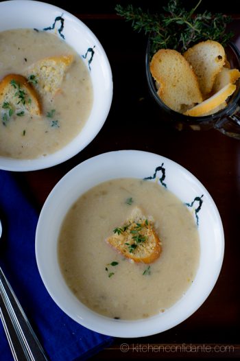 Image of creamy white bean soup in two bowls topped with parmesean croutons and fresh thyme.
