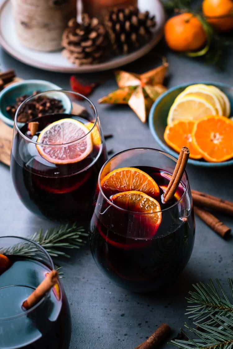 Glasses of mulled wine with citrus, cinnamon, cloves and more spices.
