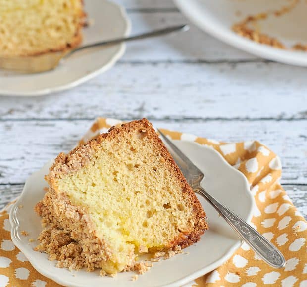 A white plate with a slice of meyer lemon coffee cake laying on it.