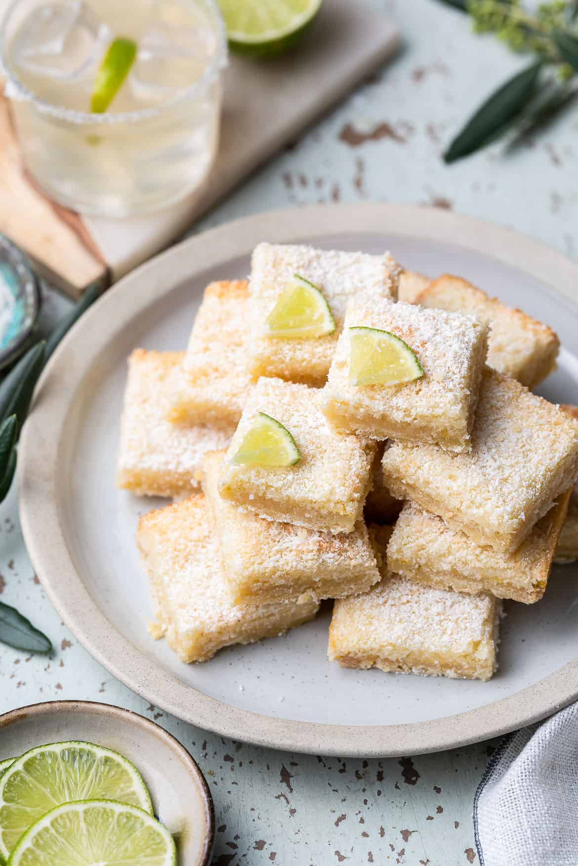 A stack of margarita bars dusted with powdered sugar on a white plate.