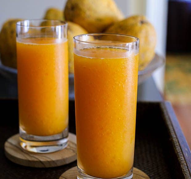 Two tall glasses filled with homemade bright orange papaya slushy.