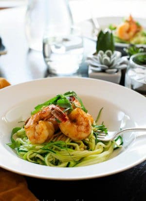 A pasta bowl full of zucchini noodles topped with shrimp.