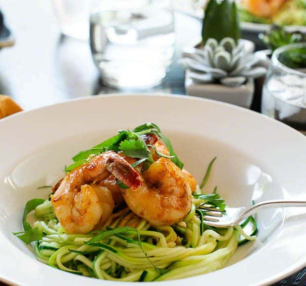 A pasta bowl full of zucchini noodles topped with shrimp.