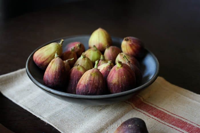 A dark bowl filled with fresh figs.