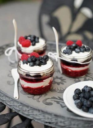 Individual servings of berry crisp parfaits in small glass jars.