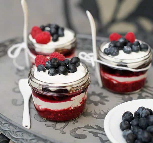 Individual servings of berry crisp parfaits in small glass jars.