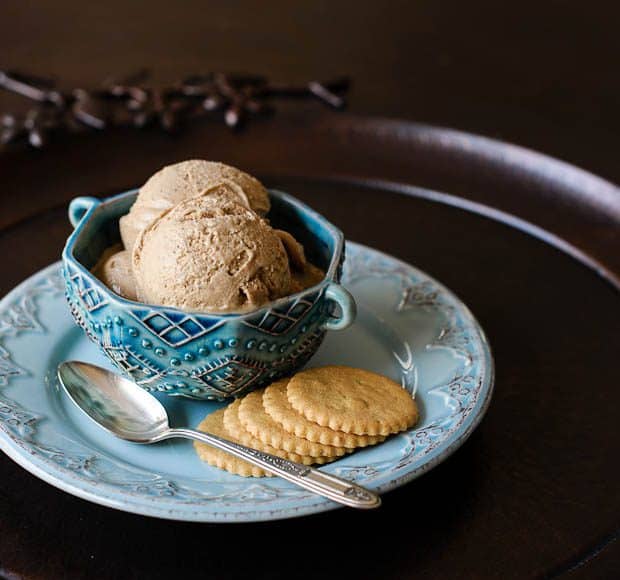 A blue dish of Chai Tea Ice Cream sits on a plate of Coconut Cookies.