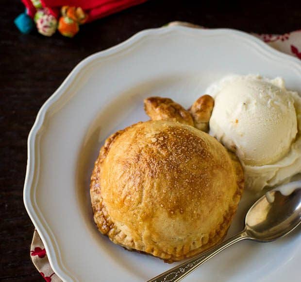 Apple Dumplings on white plates beside scoops of vanilla ice cream.