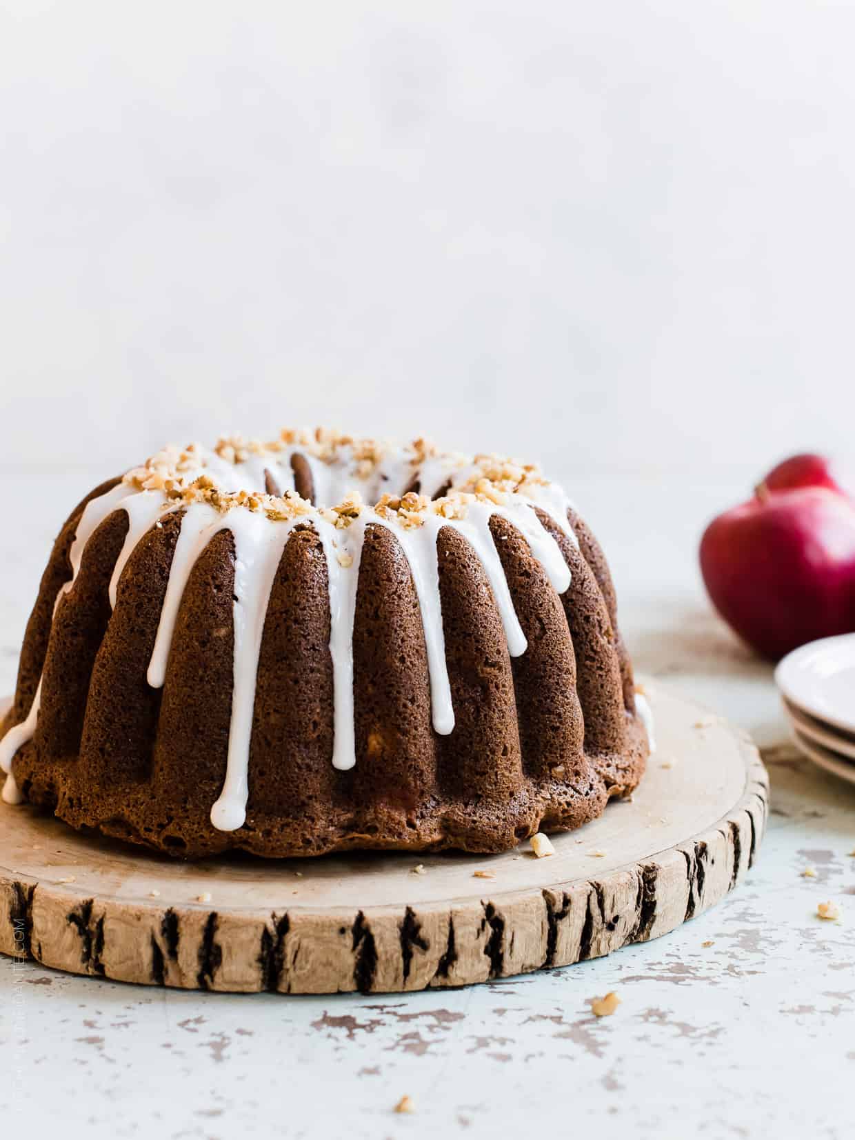 Apple Walnut Delight Cake frosted with glaze and displayed on a wooden serving board.
