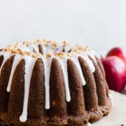 Apple Walnut Delight Cake frosted with glaze and displayed on a wooden serving board.