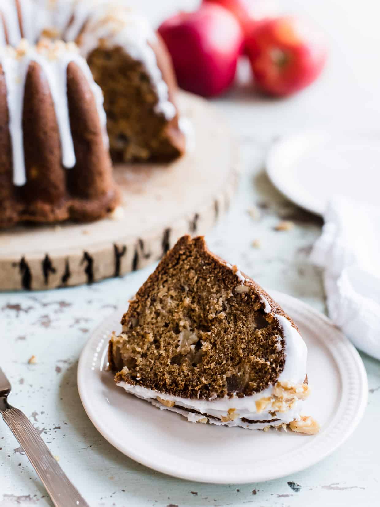 A slice of Apple Walnut Delight Cake with the remaining cake in the background.
