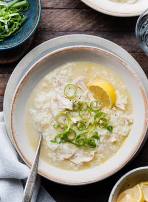 A bowl of Arroz Caldo, Filipino chicken and rice soup, topped with green onion and a slice of lemon.