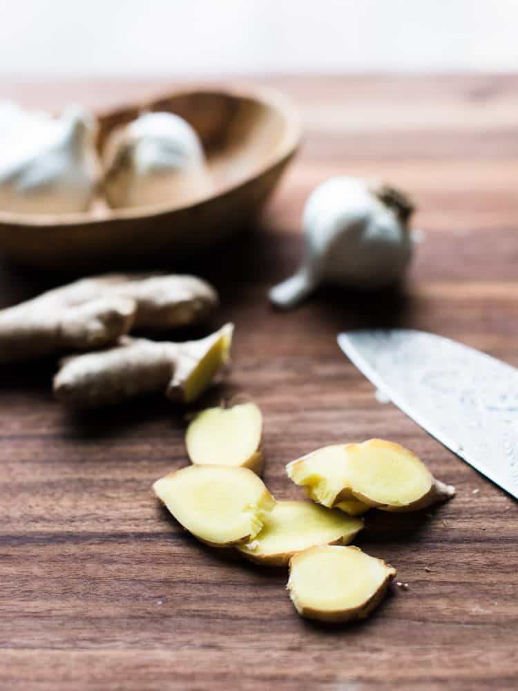 Sliced ginger on a wooden cutting board.