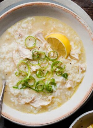 Arroz caldo with garnishes on wood table.