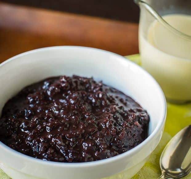 A white bowl full of Champorado: Filipino Chocolate Rice Pudding sits on a yellow napkin.