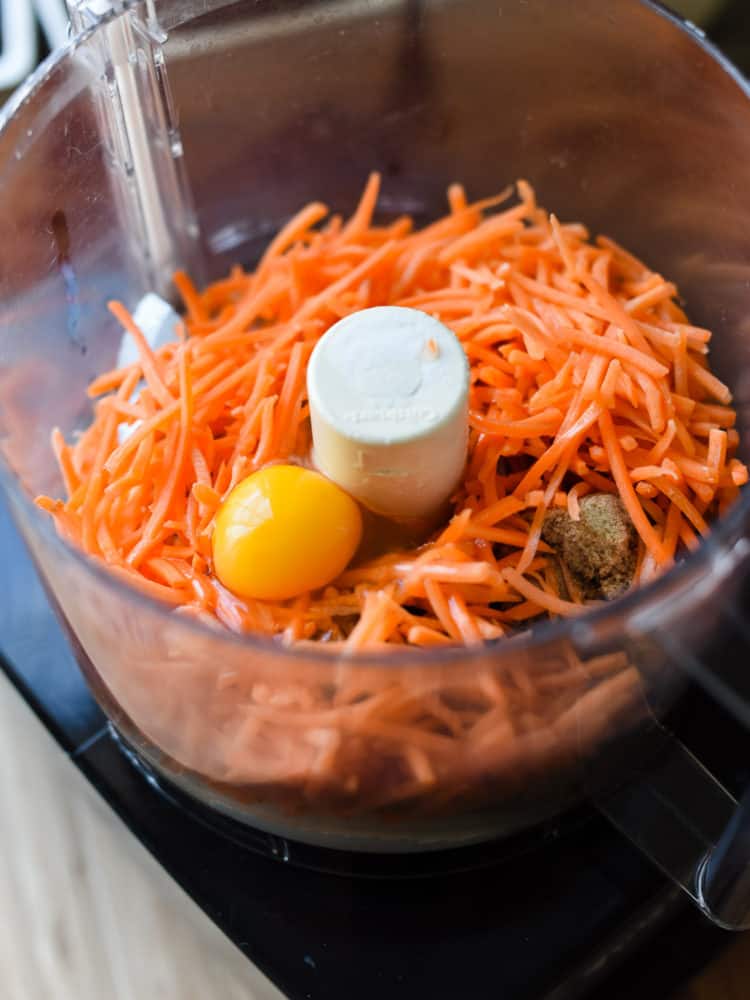 Fresh carrots and ingredients for Carrot Oat Muffins in a food processor.