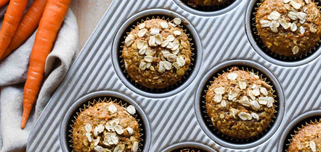 Carrot Oat Muffins in a baking pan with fresh carrots