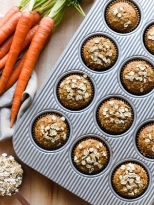 Carrot Oat Muffins in a baking pan with fresh carrots
