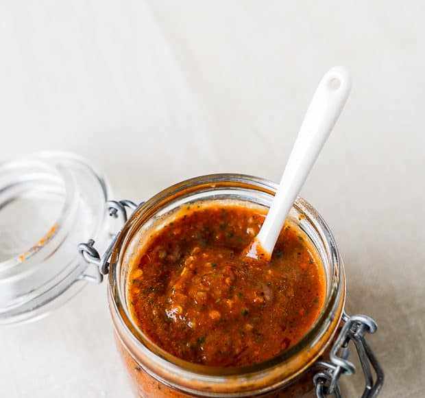 An open jar filled with homemade tomato harissa.