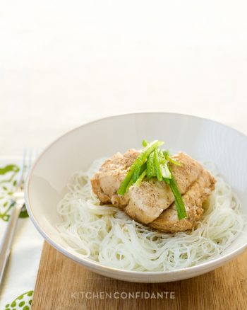 A large bowl filled with Steamed Cod with Ginger and Scallions over rice noodles.