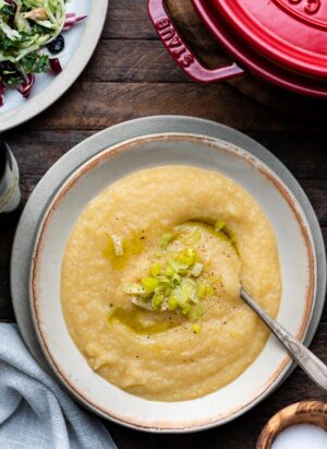 Creamy Cauliflower and Potato Soup in a bowl topped with leeks and black pepper.