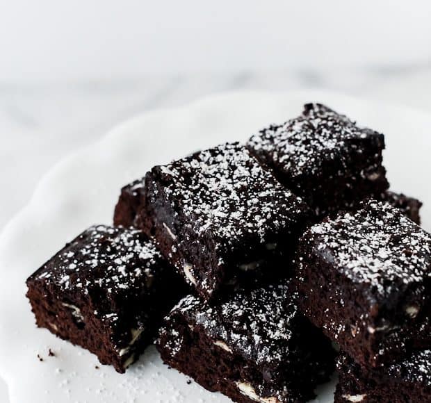 A stack of brownies with white chocolate chips and confectioner's sugar.