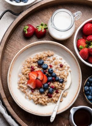 Farro Breakfast porridge in a bowl topped with blueberries and strawberries.