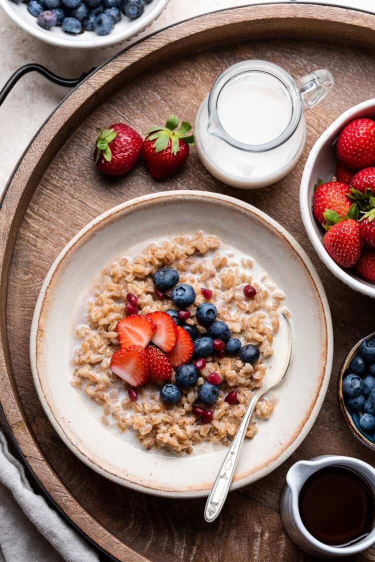 Farro Breakfast porridge in a bowl topped with blueberries and strawberries.