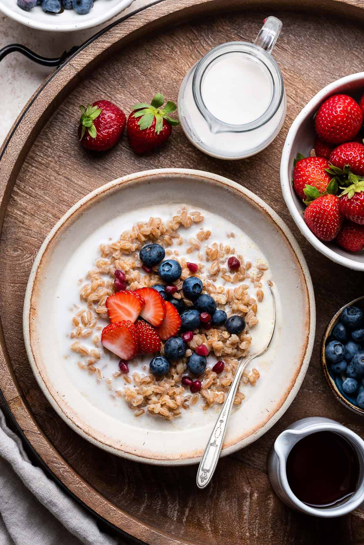 Maple Cinnamon Breakfast Farro in a white bowl topped with blueberries.