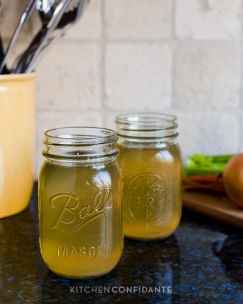 Two mason jars filled with homemade chicken stock.