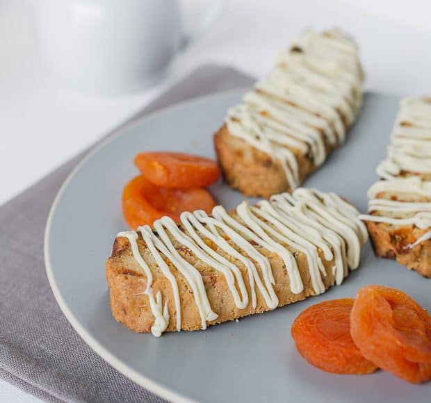 Apricot-White Chocolate Biscotti slices on a plate with dried apricots.