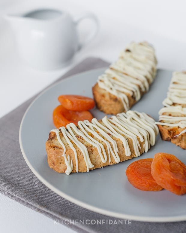 Apricot-White Chocolate Biscotti slices on a plate with dried apricots.