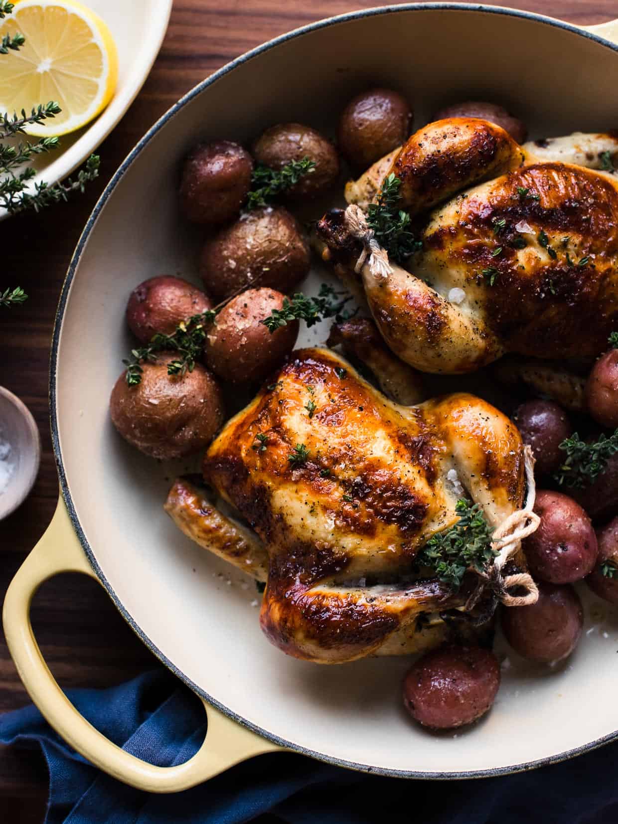Roasted Buttermilk Brined Cornish Hens and red potatoes in a yellow handled pan.
