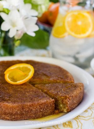 A Moroccan Orange Cake on a white serving plate with an orange slice on top.