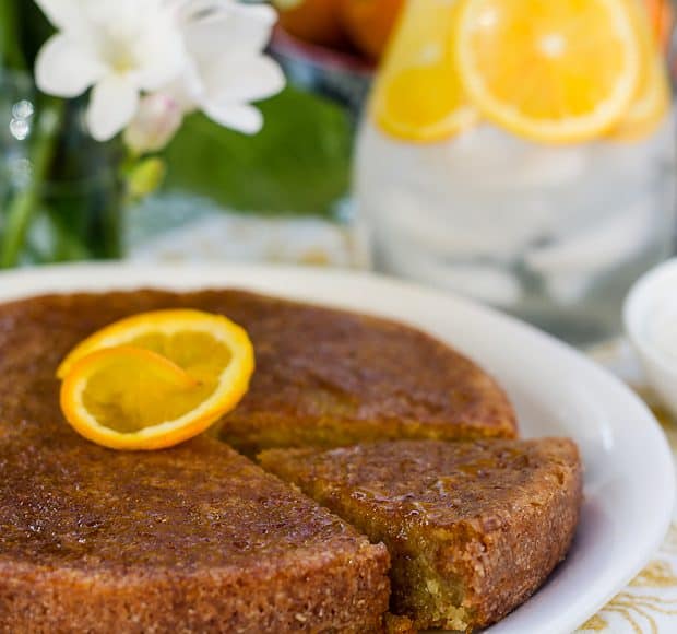 A Moroccan Orange Cake on a white serving plate with an orange slice on top.