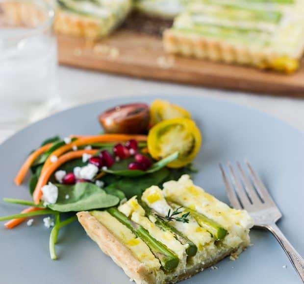 A slice of Buttermilk Asparagus Quiche on a plate with a side salad.