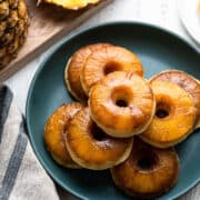 Pineapple Upside Down Cake Doughnuts stacked on a green plate.