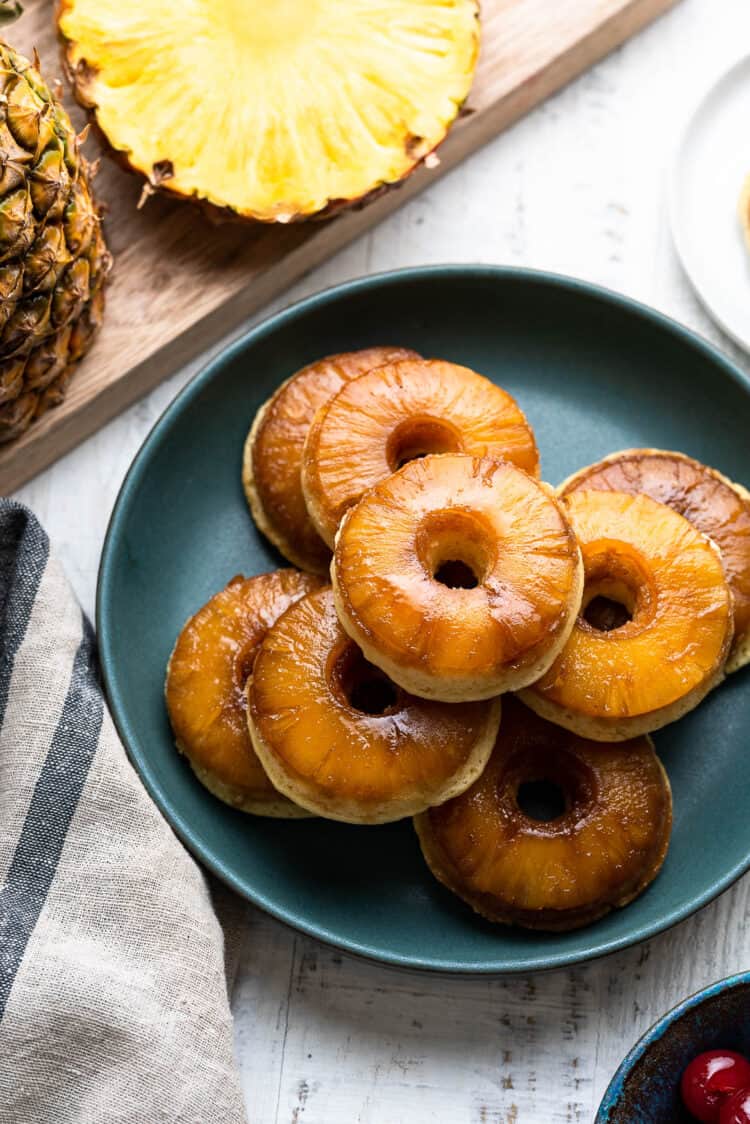 Pineapple Upside Down Cake Doughnuts stacked on a green plate.