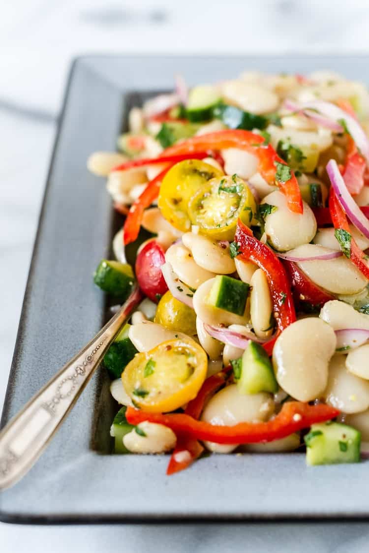 Lima Bean Salad on a serving dish with cucumbers, tomatoes and red bell peppers.