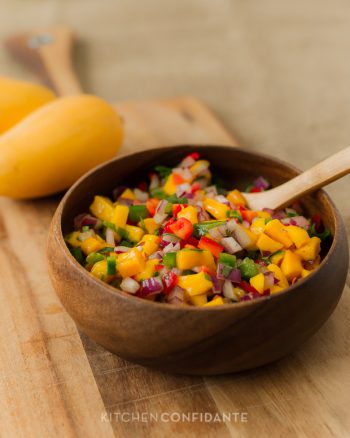 A wooden bowl filled with fresh mango salsa.