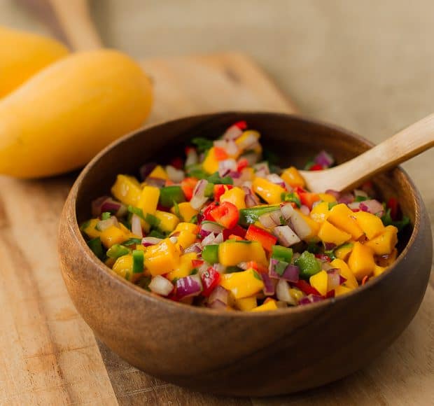 A wooden bowl filled with fresh mango salsa.