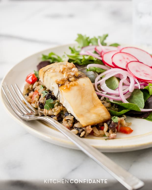 A fillet of Maple-Planked Grilled Barramundi served on a white plate with a side salad.