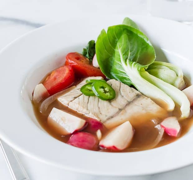 Barramundi Fish in Tamarind Broth (Sinigang na Isda) served in a white bowl.