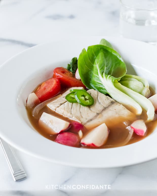 Barramundi Fish in Tamarind Broth (Sinigang na Isda) served in a white bowl.