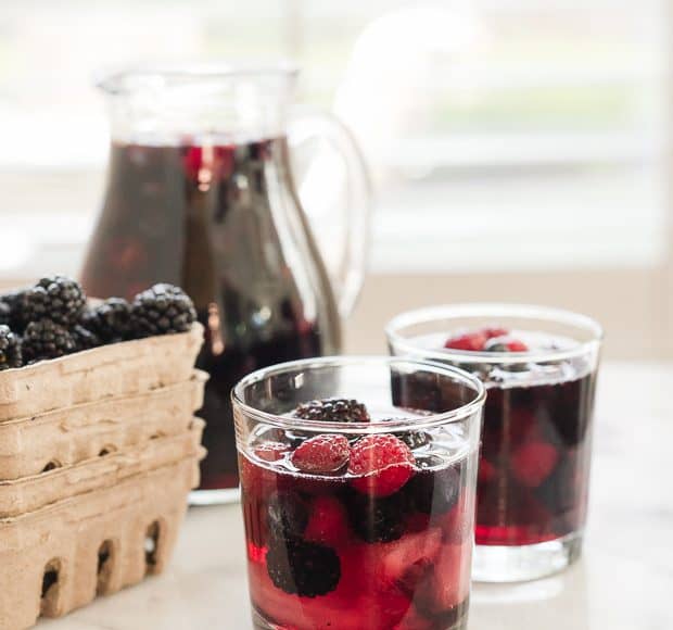 Glasses of Berry Sangria filled with bright red and blue summer berries.