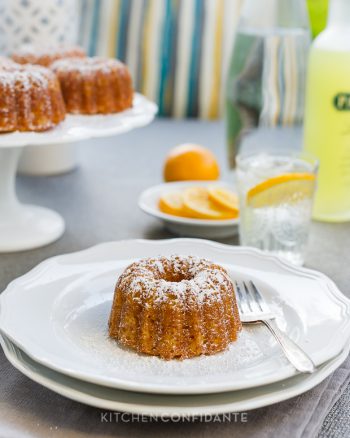 Mini lemon Bundt sprinkled with confectioner's sugar and served on a white plate.