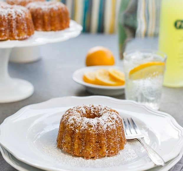 Mini lemon Bundt sprinkled with confectioner's sugar and served on a white plate.