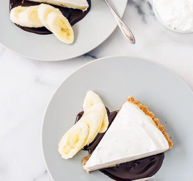 Slices of banana cream pie served with chocolate sauce and sliced bananas.